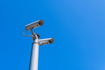 A modern CCTV security camera against blue sky background.