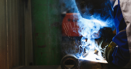 man welds at the factory working in metal industry