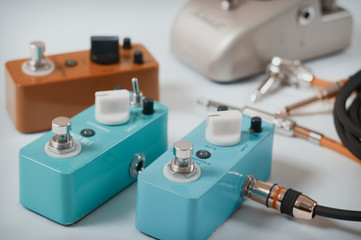 Electric guitar stomp effectors and cables in studio. Focus is on forehand switch box.