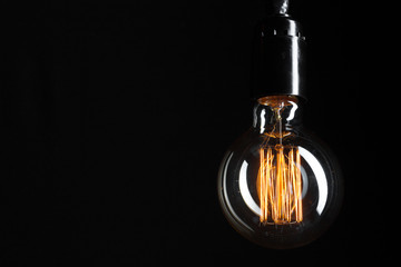 A classic Edison light bulb on dark background with space for text