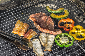 Grilled meat with vegetables over the coals on a barbecue.