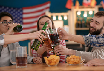 Group of cheerful friends drinking beer in bar