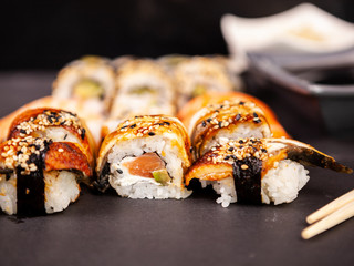 Mix variety of sushi rolls on black stone backgorund in studio