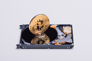 Closeup of a gold bitcoin on the hard disk drive.