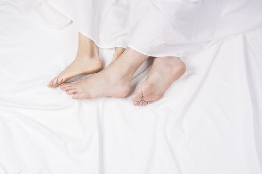 Close up of four feet in a bed. Couple sleeping