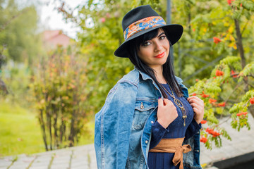 Pretty beautiful fashionable woman posing on street. Model latina, wearing stylish black Fedora hat . Female fashion concept. Outdoor close up portrait. City lifestyle. 