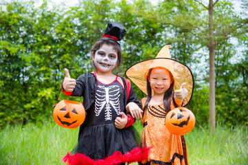 Little asian girls in Halloween costume standing in park and smile