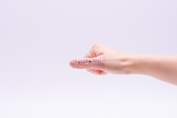Persistence concept: A band aid on thumb with hand writing "Stick with it".