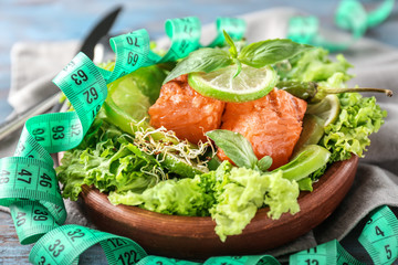 Plate with tasty fresh salad and measuring tape on table. Diet concept