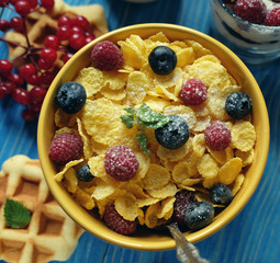 Healthy breakfast. Corn flakes with raspberries and blueberries, granola with yogurt and berries, wafers and milk. A great start to the day. Top view.