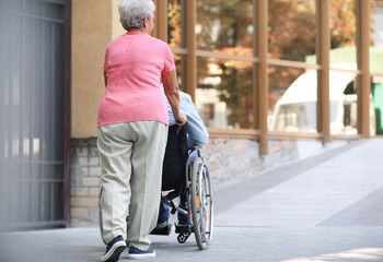 Fototapeta na wymiar Senior man in wheelchair and his wife on ramp outdoors