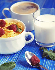 Healthy eating, food and diet concept - Cornflakes with berries, milk and coffee for breakfast. Blue wooden background.