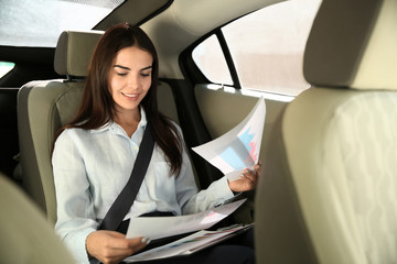 Young businesswoman working with documents in car