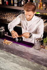 Barman adding cocktail ingredients.Barman in bar interior making alcohol cocktail.