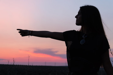 beautiful young brunette girl posing a road in the middle of the field at sunset, silhouette