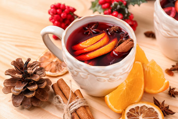 Cup of delicious mulled wine on wooden table