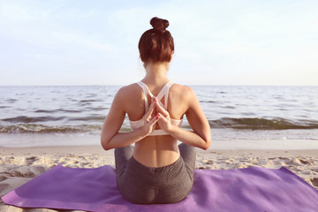 Fototapeta na wymiar Woman practicing yoga on sea shore