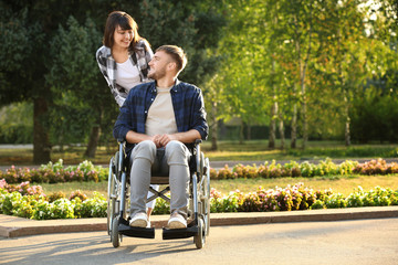 Young man in wheelchair and his wife outdoors