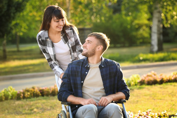 Young man in wheelchair and his wife outdoors