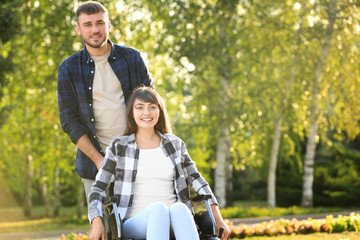 Young woman in wheelchair and her husband outdoors