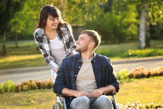 Young Man In Wheelchair And His Wife Outdoors