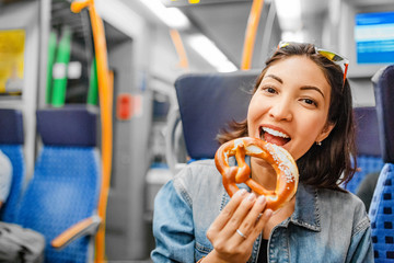 woman eating pretzel while traveling by train © EdNurg