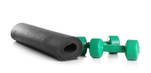 Yoga mat with dumbbells on white background