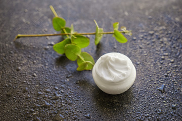 Jar with body cream on dark table