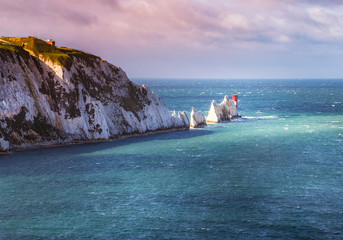 A break in the clouds illuminates the iconic chalk stone pinnacles of The Needles and the 19th...