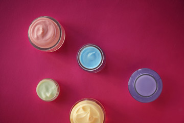 Jars with body cream on color table