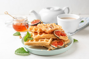 Delicious waffles with fig slices on plate