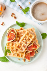Delicious waffles with fig slices and cup of coffee on light table