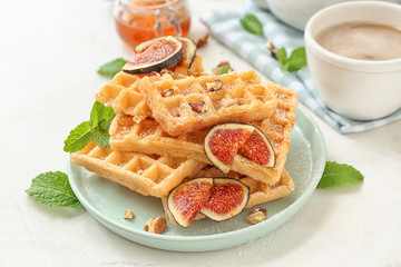 Delicious waffles with fig slices on plate