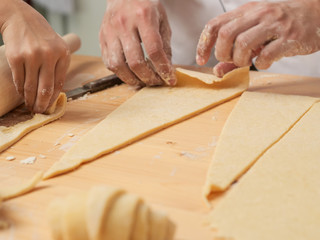 Chef hands are rolling a croissant from dough on wooden board. black background.