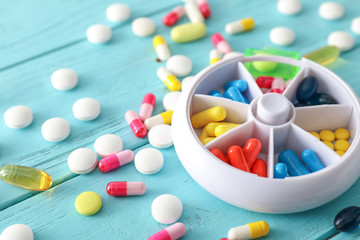 Plastic container with pills on color wooden background
