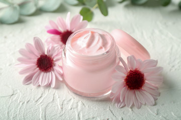 Obraz na płótnie Canvas Jar with body cream and flowers on white table