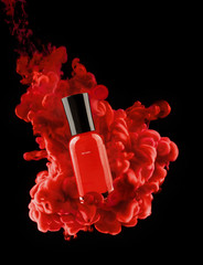 red nail polish bottle in clouds of paint.