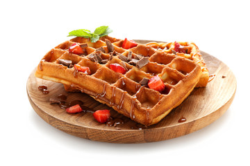 Delicious waffles with strawberries and caramel sauce on white background