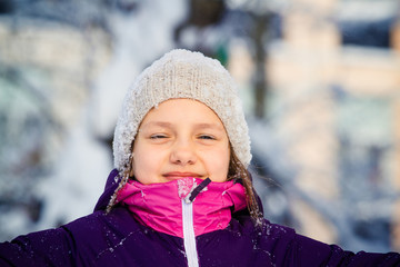 Girl in pink overalls playing and having fun in the snow