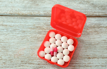 Plastic container with different pills on wooden table