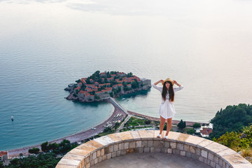 Naklejka premium attractive woman standing on viewpoint near saint stephen island in Adriatic sea, Budva, Montenegro