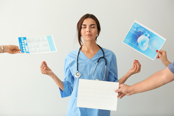 Female nurse with lot of work meditating on light background