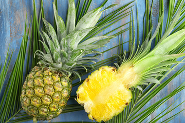 Ripe pineapples and tropical leaves on wooden background