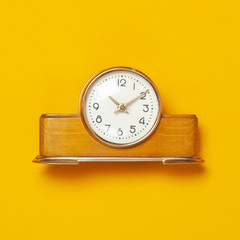 Wooden retro alarm clock on bright yellow minimalistic background top view Flat Lay with copy space. The concept of time, morning, education.