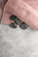 Clean soft towel and spa stones on color background
