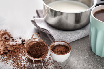 Cup of hot chocolate with ingredients on grey table