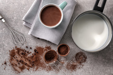 Cup of hot chocolate with ingredients on grey table