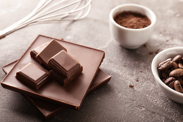 Chocolate with cacao powder and roasted coffee beans on grey table