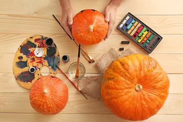 Woman with pumpkins, paints and color chalks on wooden background
