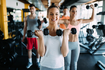 Young woman doing exercise with dumbbell in gym